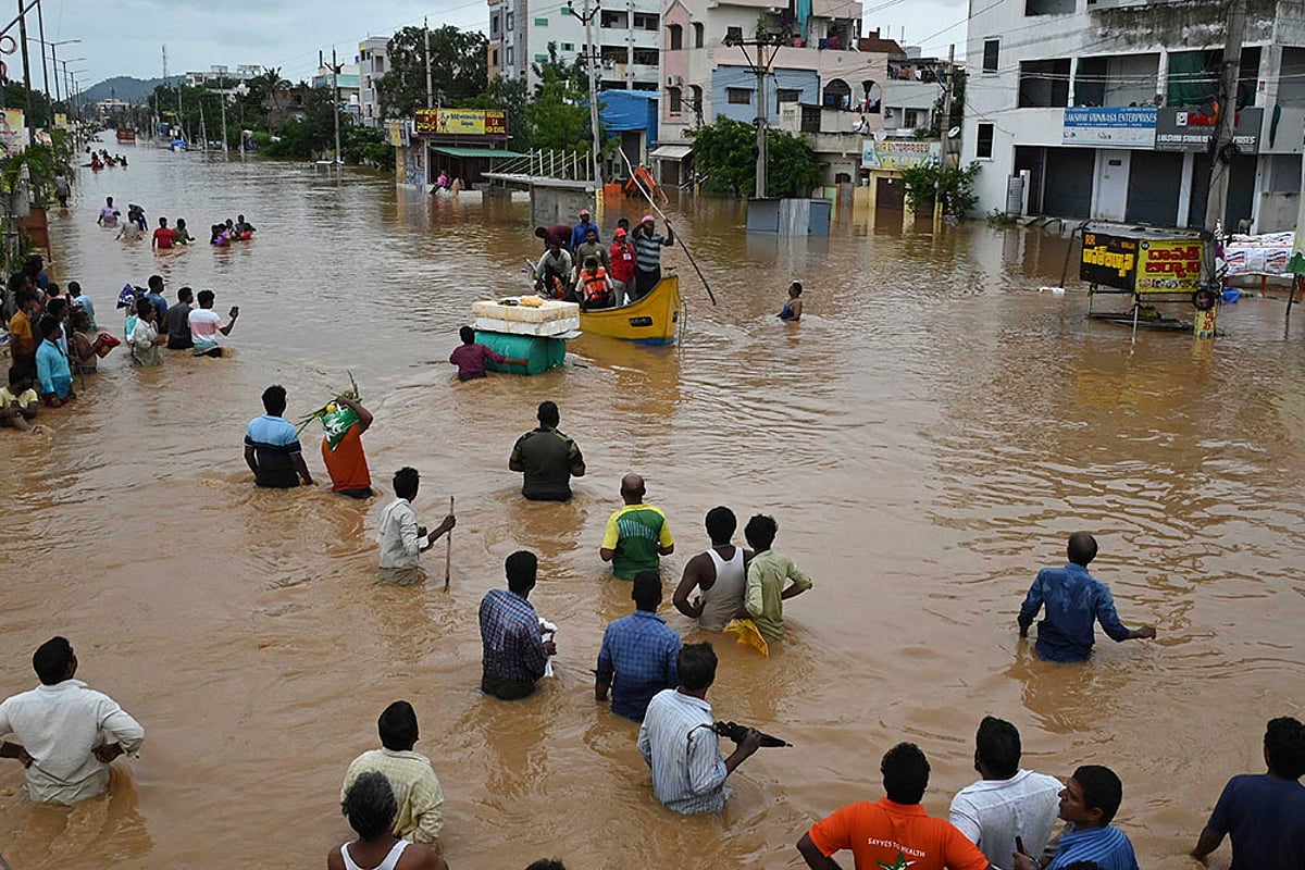 People wade through a flooded road in Vijayawada, Andhra Pradesh